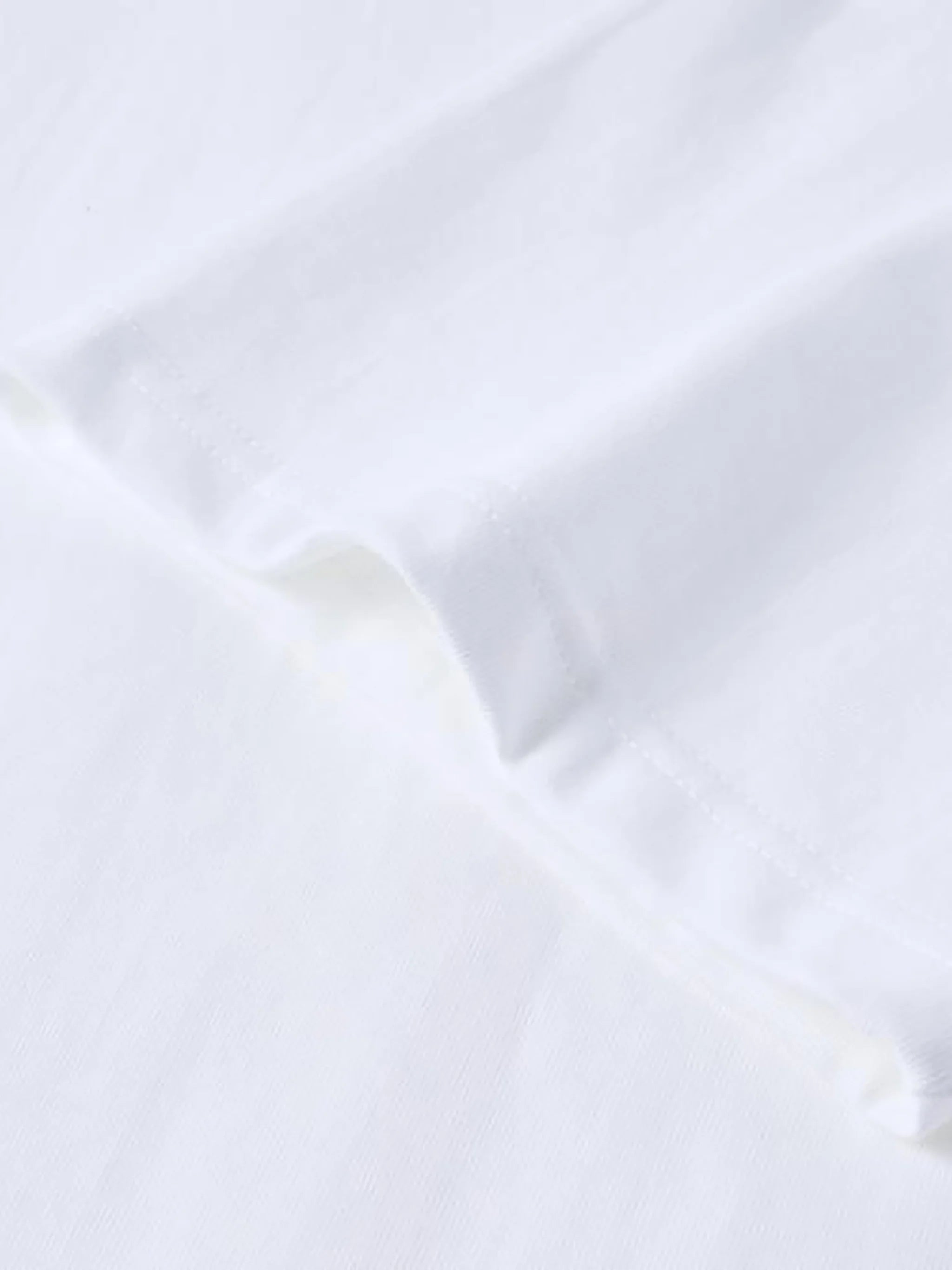 Close-up of white cotton T-shirt fabric with hem and seam details