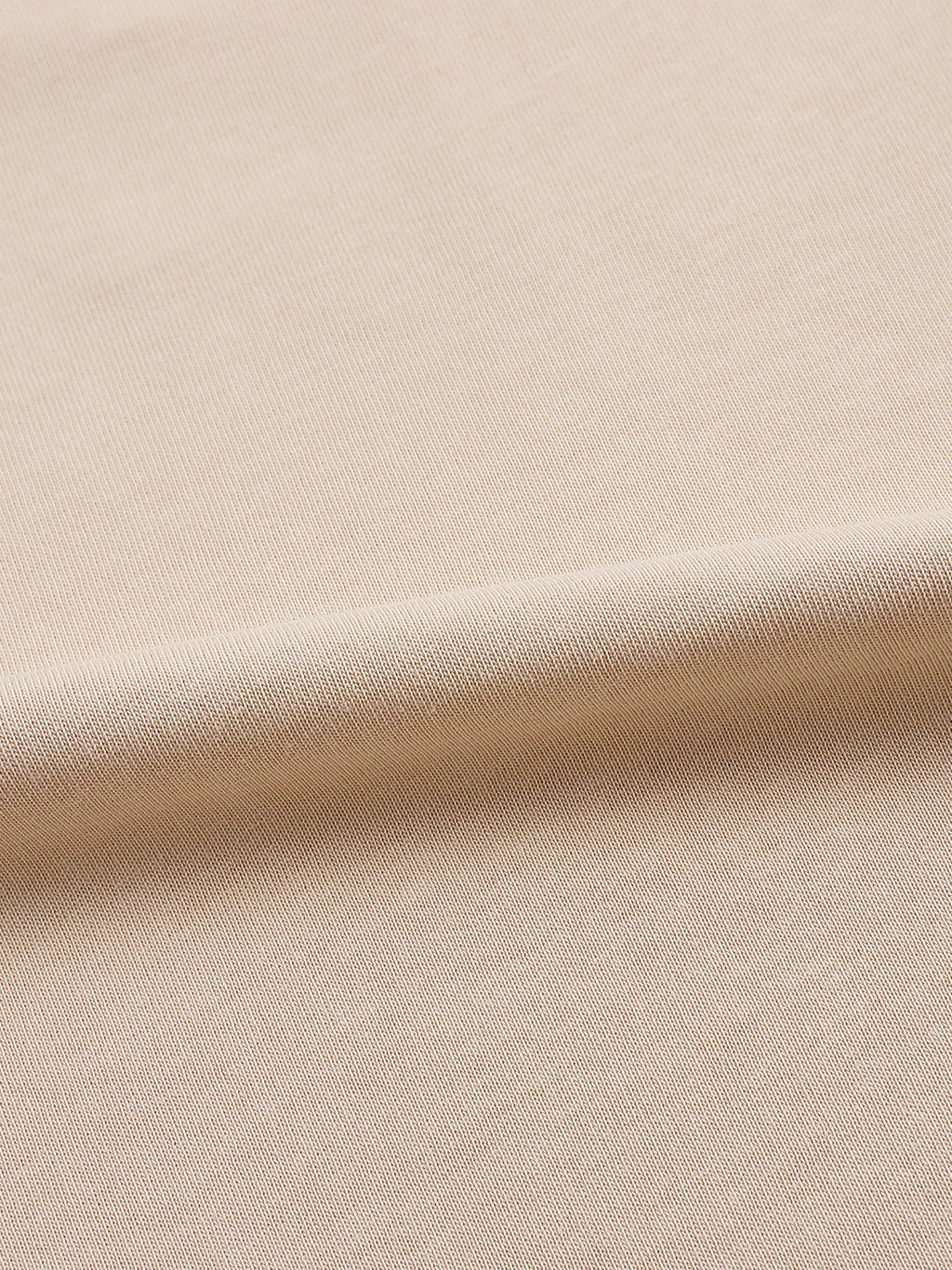Close-up of beige textured fabric, smooth knit material for apparel or garments
