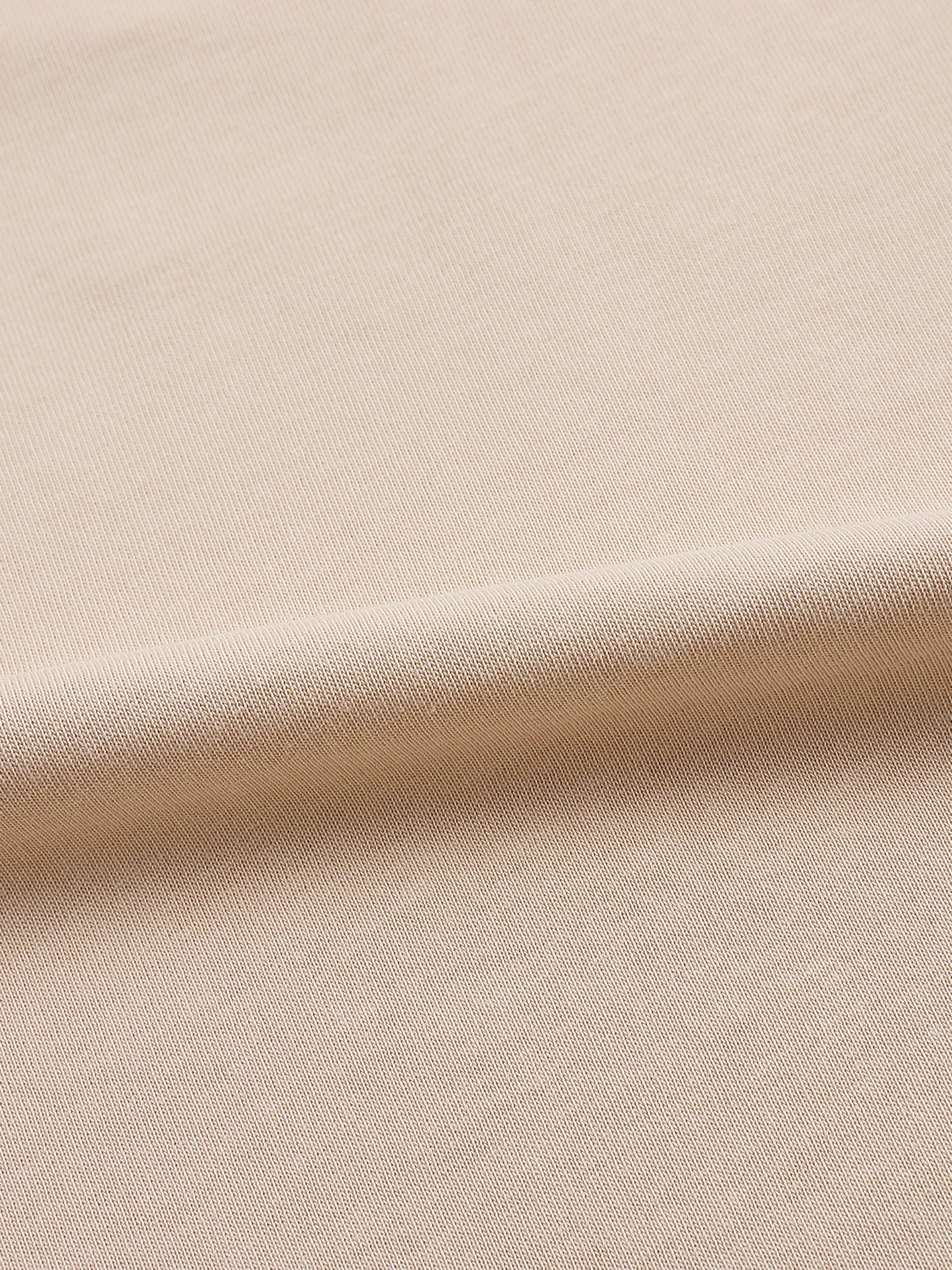 Close-up of beige textured fabric, smooth knit material for apparel or garments